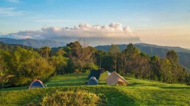 Chiang Mai, Tayland - 4 Aralık 2022 - Tayland 'ın en yüksek üçüncü dağı olan Doi Luang Chiang Dao, dramatik bulutlar ve renkli gökyüzü ile ön planda kamp çadırları ile görülüyor
