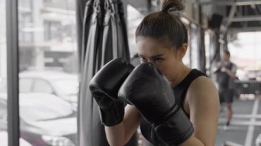 Genç çekici bayan boksör yerel spor salonuna yumruk ve tekme pratiği yapıyor, ağır çekimde vurulmuş.