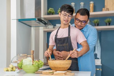 Mutlu, genç, aynı cinsiyetten bir çift, kaliteli zamanlarını birlikte yemek pişirerek ve konuşarak geçiriyor. LGBTQ konsepti.