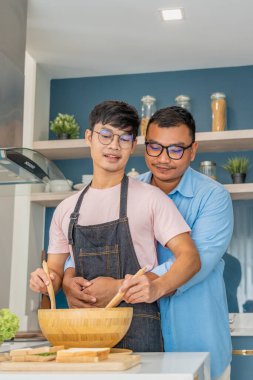 Mutlu, genç, aynı cinsiyetten bir çift, kaliteli zamanlarını birlikte yemek pişirerek ve konuşarak geçiriyor. LGBTQ konsepti.