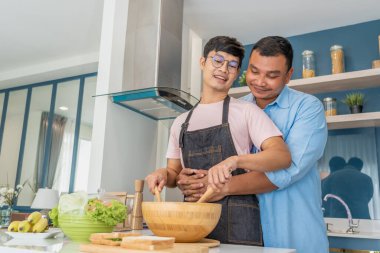 Mutlu, genç, aynı cinsiyetten bir çift, kaliteli zamanlarını birlikte yemek pişirerek ve konuşarak geçiriyor. LGBTQ konsepti.