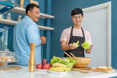 Mutlu, genç, aynı cinsiyetten bir çift, kaliteli zamanlarını birlikte yemek pişirerek ve konuşarak geçiriyor. LGBTQ konsepti.