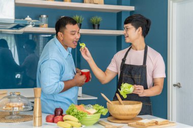 Mutlu, genç, aynı cinsiyetten bir çift, kaliteli zamanlarını birlikte yemek pişirerek ve konuşarak geçiriyor. LGBTQ konsepti.