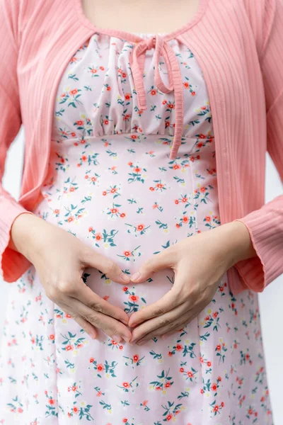 妊娠中の女性で妊娠中のドレスで彼女の手でハート形上の彼女の腹立ち上の白い背景 母愛の概念 — ストック写真