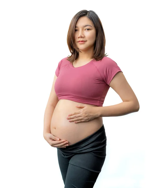 幸せな妊娠中の女性でフィットネス服立って彼女の露出腹に対して白い背景 部屋のためにコピースペース — ストック写真
