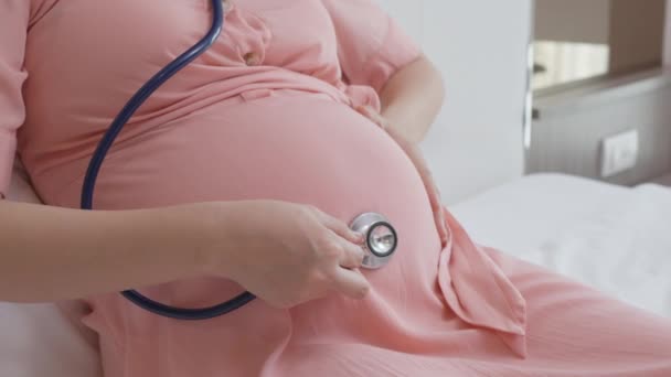 Молодая Беременная Женщина Используя Стетоскоп Слушает Звук Своего Нерожденного Ребенка — стоковое видео