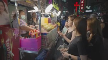 Bangkok, Tayland - 25 Mart 2023 - Asyalı ya da Çinli turistler Tayland 'ın Bangkok kentindeki ünlü Yaowarat Yolu' ndaki bir sokak yemekhanesinden portakal suyu alıyorlar.