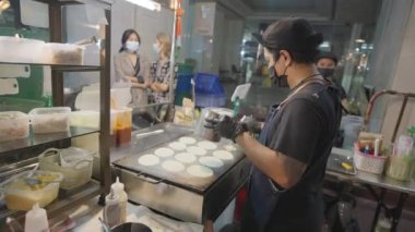 Bangkok, Tayland - 25 Mart 2023 Tay dilinde Kanom Beuang olarak bilinen geleneksel tatlı krepi yapan yerel bir erkek sokak yemeği satıcısı.