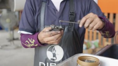 Chiang Mai, Tayland - 27 Nisan 2023 - Erkek oto tamircisi bir mola ayakkabısının bağlantı noktalarına yağ sürüyor