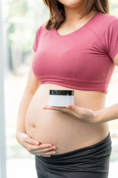 妊娠中のストレッチマークを減らすために白いボディジェルとクリーム製品を保持フィットネス服の妊婦の閉鎖 — ストック写真