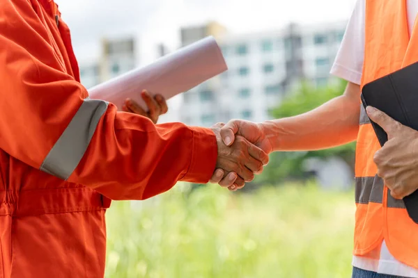 stock image Close up hands of 2 male engineers or construction workers outside with blurred buildings in the background