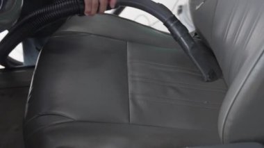 Elektrikli süpürgeyi araba koltuğundaki kirleri emmek için kullanan biri.