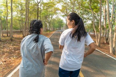 Bir parkta sabah koşusu yapan iki genç kadının arka görüntüsü.