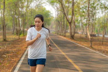Genç bir kadın yazın yerel koşu parkında tek başına koşuyor.
