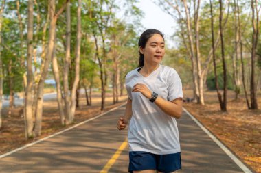Genç bir kadın yazın yerel koşu parkında tek başına koşuyor.