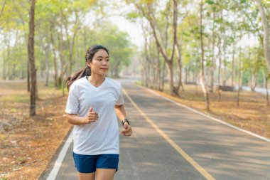 Genç bir kadın yazın yerel koşu parkında tek başına koşuyor.
