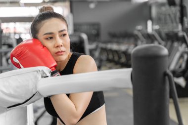 Spor salonundaki boks ringinde dinlenen güzel bir bayan boksörün portresi.