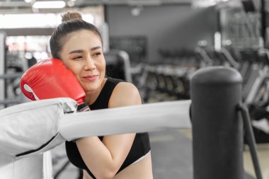 Spor salonundaki boks ringinde dinlenen güzel bir bayan boksörün portresi.