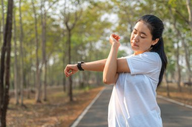 Genç bayan koşucu sabah koşusuna başlamadan önce kollarını ve bacaklarını esnetiyor.