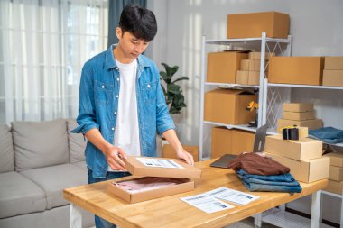 Genç online satıcı gömleğini kutuya koyup müşterisine kendi stüdyosundan yolluyor.
