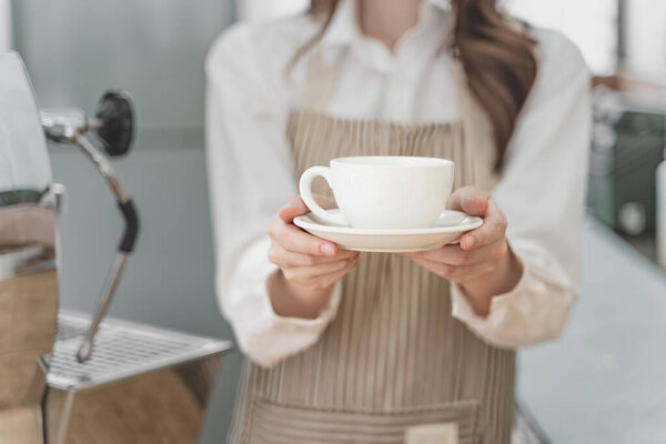 Close up hands of a female barista holding a cup of coffee to serve her customer