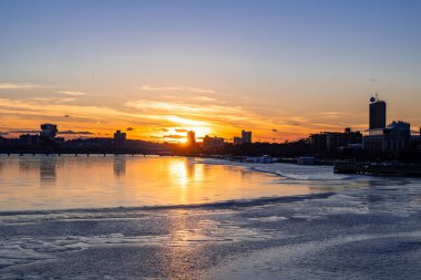 Boston, Massachusetts - 14 February 2025 - Silhouette view of Boston city skyline with high-rise buildings seen from  Longfellow bridge over Charles river during winter sunset clipart