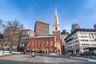 Boston, MA, ABD - 11 Şubat 2025 - Boston 'daki Park Street Kilisesi' nin ve Boston 'daki binaların manzarası açık mavi gökyüzüne karla çevrili