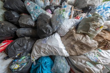 Nan, Tayland - 8 Haziran 2025 - Bir kirlilik ve geri dönüşüm krizini gösteren, plastik şişeler ve diğer atık dolu büyük siyah, beyaz ve temiz çöp yığını.