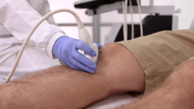Hastanedeki erkek hastanın dizini kontrol eden sonograf. Diz ekleminin ultrason teşhisi