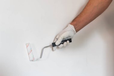 Bir ustanın elinde duvarları boyamak için bir silindir. 