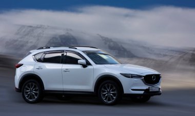 Arka planda bulanık hareket etmiş Mazda beyaz arabası.