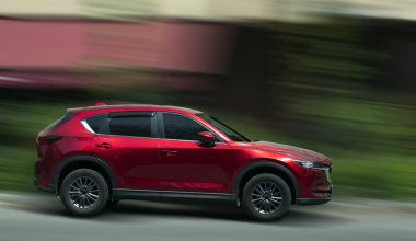 Arka planda bulanık hareket etmiş Mazda kırmızı arabası.