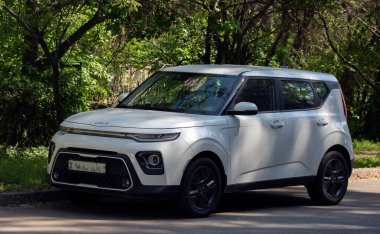 Yeşil ağaçların arka planında Kia beyaz araba.