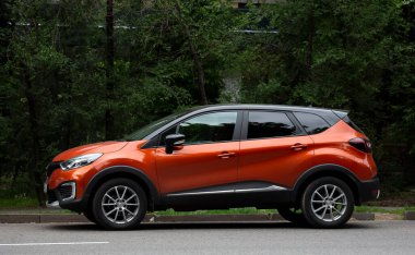 Yeşil ağaçların arka planında kırmızı araba renault.