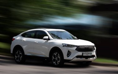 Arka planda bulanık hareket eden beyaz bir araba.