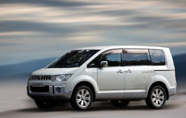 Mitsubishi Delica beyaz minibüsü hareket bulanık arkaplanda.