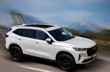 Arka planda bulanık hareket eden beyaz bir araba.