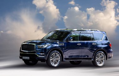 Bulutların arkasında Infiniti mavisi araba.