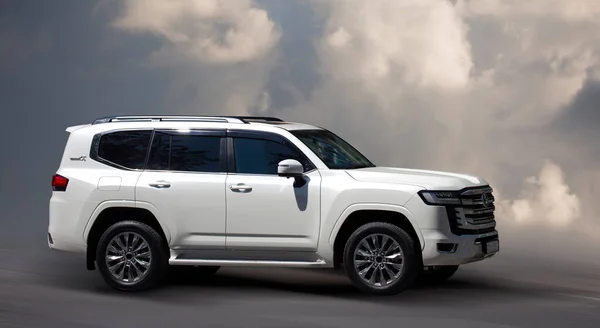 stock image Toyota Land Cruiser-300, white car on the background of clouds.