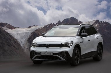 Dağların arka planında beyaz elektrikli araba.