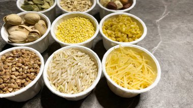 Sağlıklı beslenme için çeşitli tahıllar, siyah mermerden yapılmış bir taş masanın arka planında.