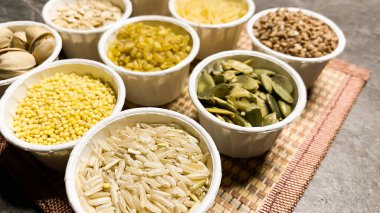 Sağlıklı beslenme için çeşitli tahıllar, siyah mermerden yapılmış bir taş masanın arka planında.