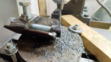 Bir matkap ucu matkap makinesinde mengeneye sıkıştırılmış bir bölümü deliyor