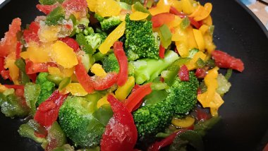 Donmuş brokoli, biber ve diğer sebzeler bir tavada pişirilir.