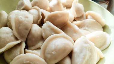 Doldurulmuş taze kaynamış hamur köfteleri derin bir tabağa konur. Yüzeyleri pürüzsüz ve hafif parlak.