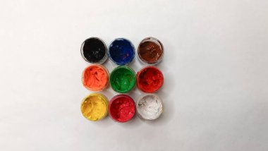 Açık kavanozlarda çok renkli guaj ve beyaz arka planda fırçalar