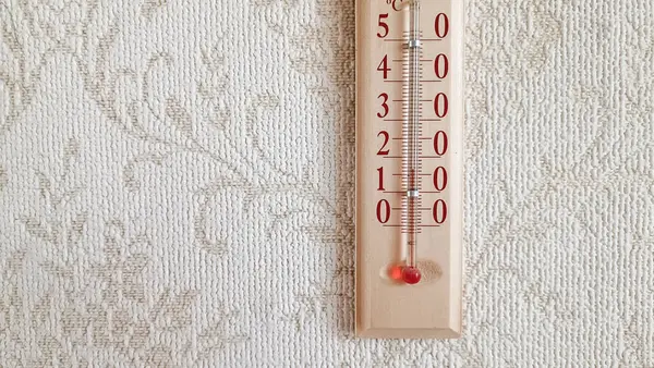 Termometre duvar kâğıdı ya da desenli yüzeyi olan bir duvarda asılı.