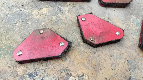 Farklı boyutlarda beş manyetik kaynak köşesi gri bir arka planda, benekli, metal kaplamalı kırmızı köşeli.