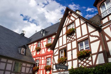 BEILSTEIN, GERMANY - SEPTEMBER 03 2022: Moselle nehri kıyısındaki tarihi köy eski ahşap evleri ve tepelerin tepesinde Metternich kalesinin kalıntıları var.