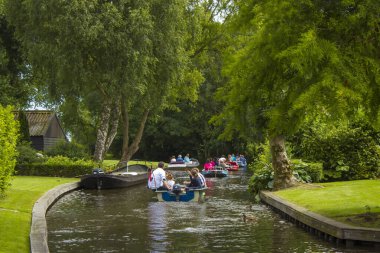 GIETHOORN, NETHERLANDS - 1 Ağustos 2017: Giethoorn 'daki bir kanalda tekne gezisinde bilinmeyen ziyaretçiler. Güzel evler ve bahçıvanlık şehri 